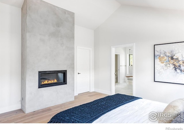 bedroom featuring a fireplace, high vaulted ceiling, and light hardwood / wood-style flooring