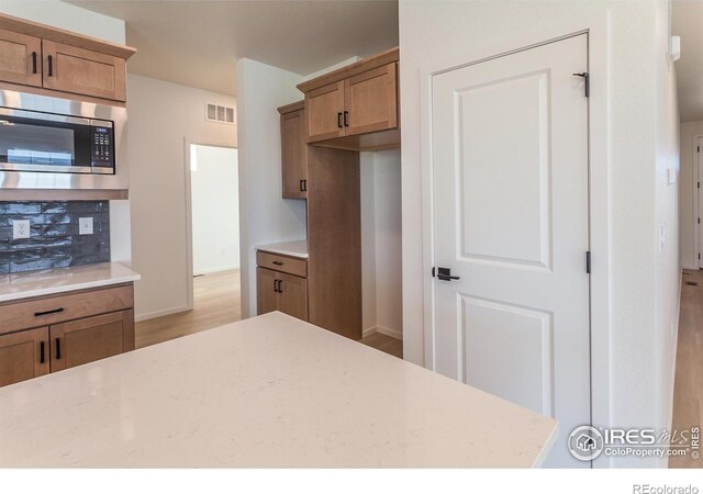 kitchen with stainless steel microwave and light hardwood / wood-style floors