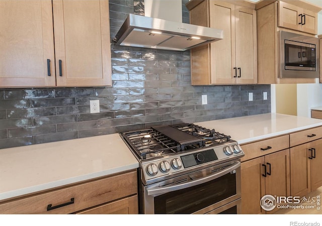 kitchen with tasteful backsplash, light brown cabinetry, stainless steel appliances, and wall chimney exhaust hood