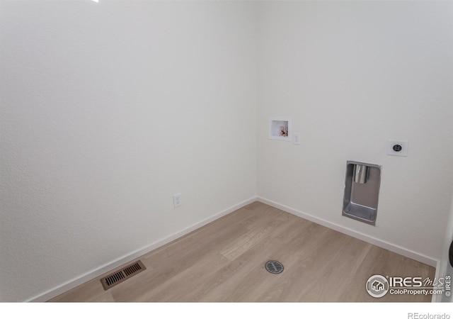 clothes washing area with electric dryer hookup, washer hookup, and light hardwood / wood-style flooring