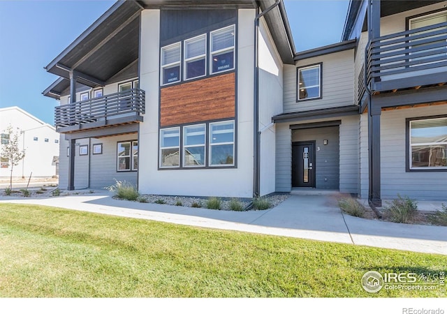 view of front of property featuring a front lawn and a balcony