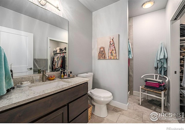 full bath with vanity, baseboards, a shower, a walk in closet, and toilet