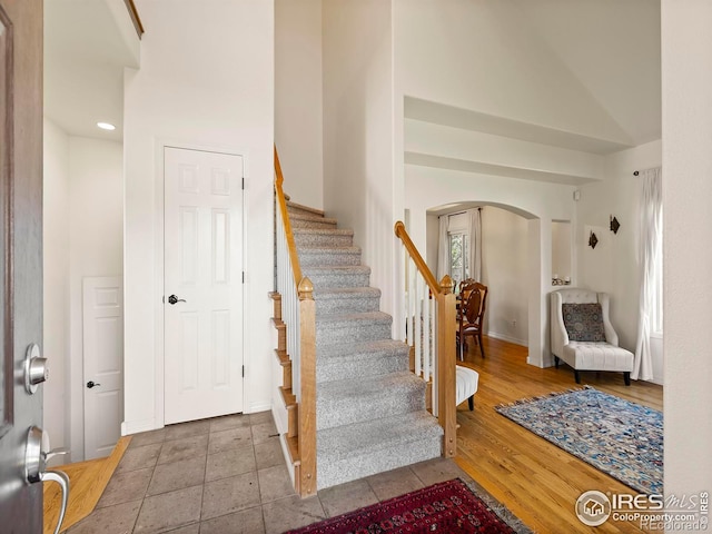 staircase with wood-type flooring and high vaulted ceiling