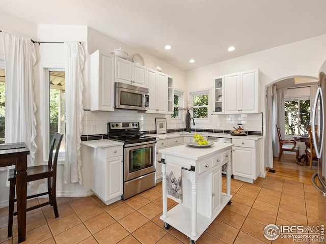 kitchen with white cabinetry, appliances with stainless steel finishes, a center island, and light tile patterned floors