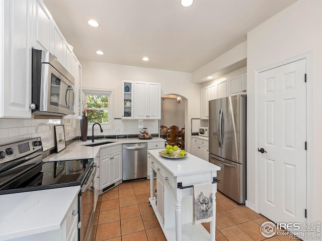 kitchen featuring sink, light tile patterned floors, stainless steel appliances, a center island, and white cabinets