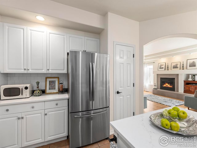 kitchen with white cabinets, tasteful backsplash, and stainless steel fridge