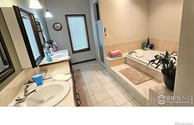 bathroom with tiled tub, vanity, and tile patterned flooring