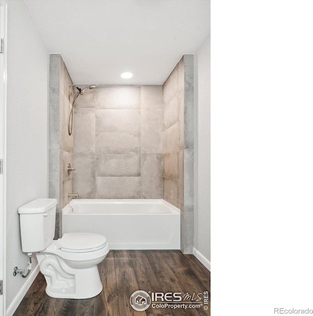 bathroom featuring hardwood / wood-style floors, tiled shower / bath combo, and toilet