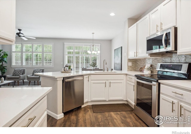 kitchen with kitchen peninsula, appliances with stainless steel finishes, white cabinets, and sink