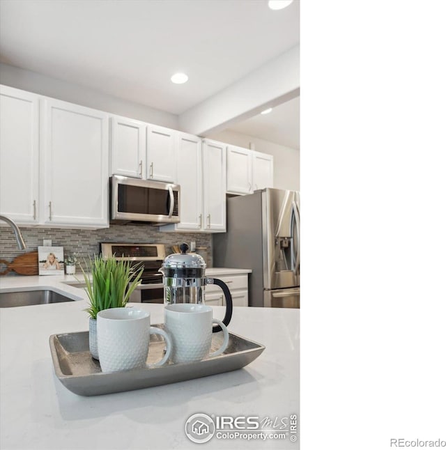 kitchen with sink, stainless steel appliances, white cabinetry, and decorative backsplash