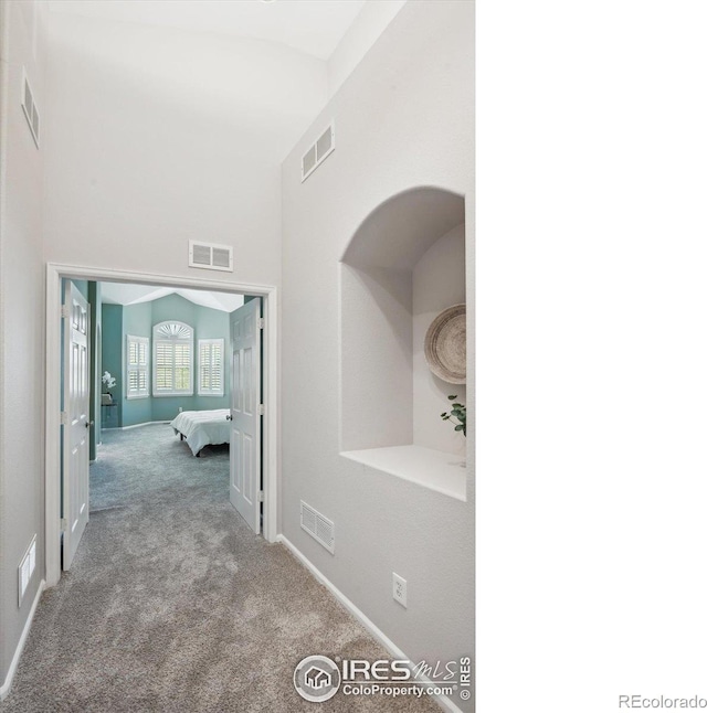 hall featuring lofted ceiling and light colored carpet