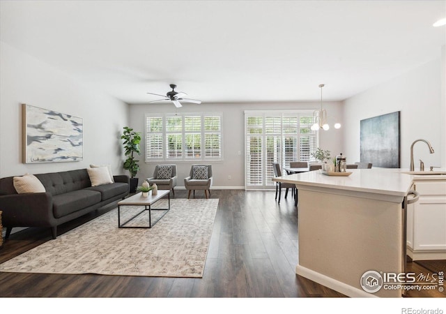 living room featuring a healthy amount of sunlight, ceiling fan with notable chandelier, dark hardwood / wood-style floors, and sink