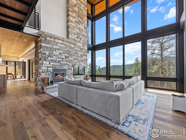 living room featuring high vaulted ceiling, wood-type flooring, a stone fireplace, and wood ceiling