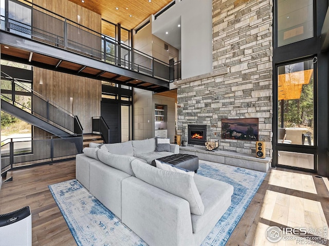 living room with a towering ceiling, a fireplace, and hardwood / wood-style flooring