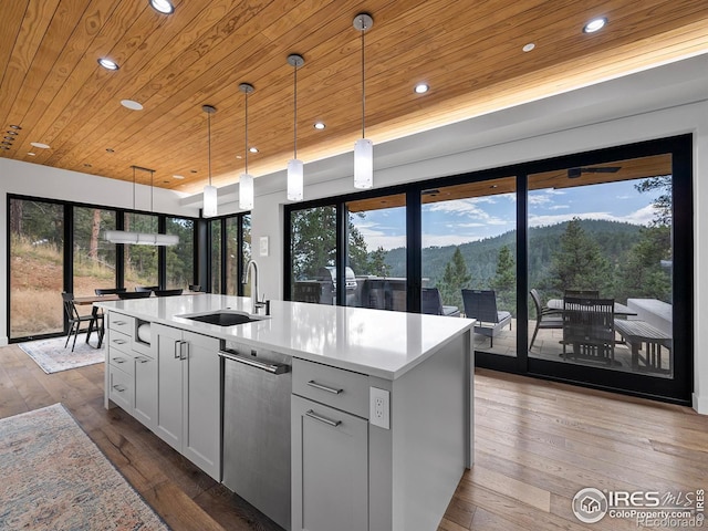 kitchen with a kitchen island with sink, hanging light fixtures, and wood-type flooring