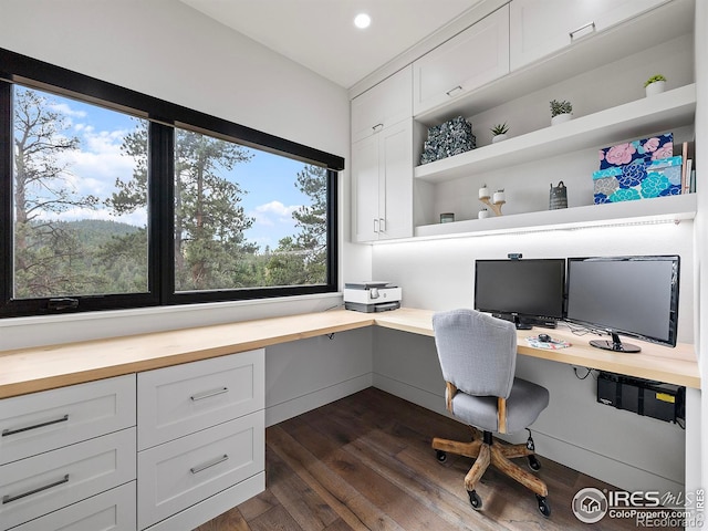 home office featuring dark hardwood / wood-style flooring, built in desk, and a healthy amount of sunlight