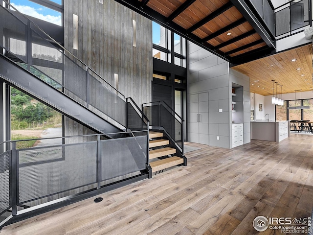 entryway featuring beamed ceiling, wood ceiling, wood-type flooring, sink, and a towering ceiling