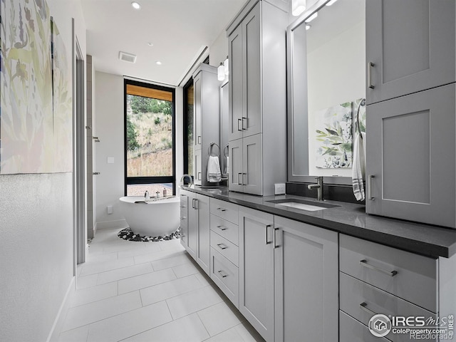 bathroom with double sink vanity, tile patterned floors, and a washtub