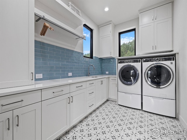 laundry area with light tile patterned floors, washer and clothes dryer, cabinets, and sink