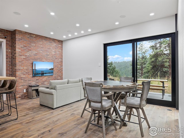 dining space with light hardwood / wood-style flooring and brick wall