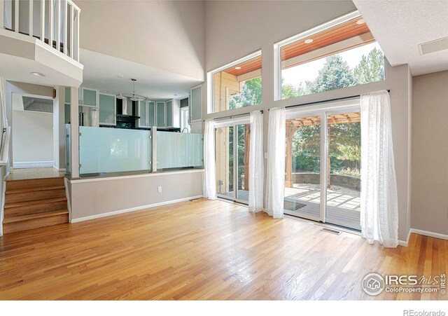 unfurnished living room with light hardwood / wood-style flooring and a towering ceiling