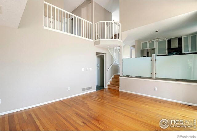 unfurnished living room featuring hardwood / wood-style floors and a towering ceiling