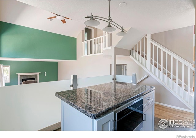 kitchen with light wood-type flooring, a fireplace, a textured ceiling, and a kitchen island