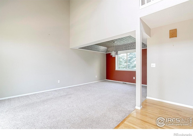 carpeted spare room featuring a towering ceiling