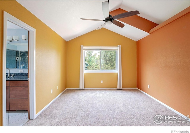 spare room featuring ceiling fan, light carpet, and vaulted ceiling