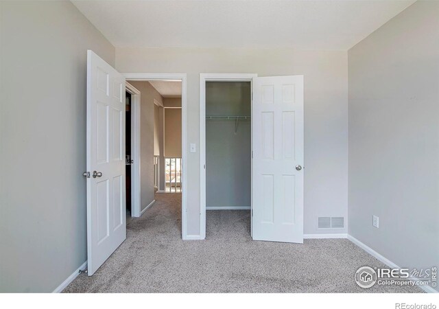 unfurnished bedroom featuring light carpet and a closet