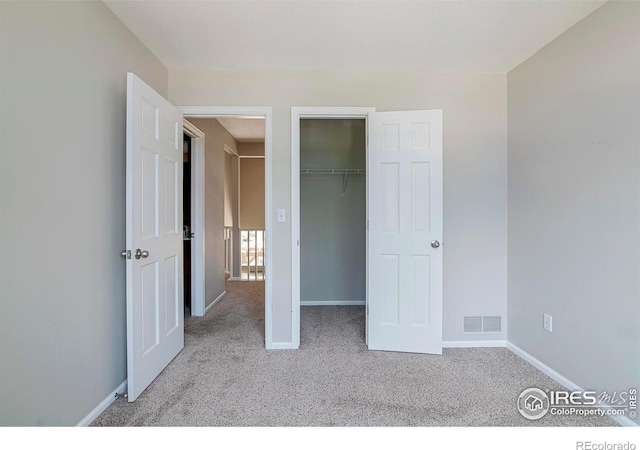 unfurnished bedroom with light carpet, a walk in closet, and a closet