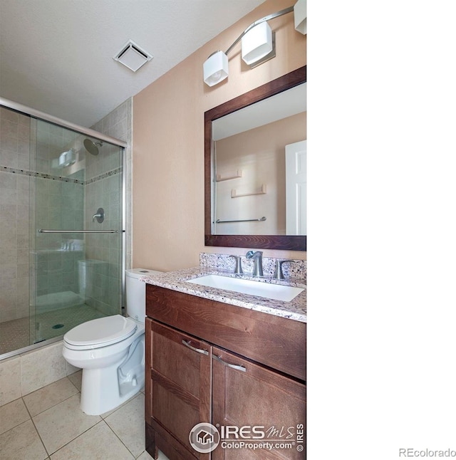 bathroom featuring vanity, walk in shower, toilet, and tile patterned flooring