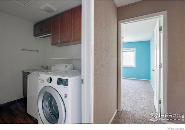 clothes washing area featuring dark colored carpet, washer and clothes dryer, and cabinets