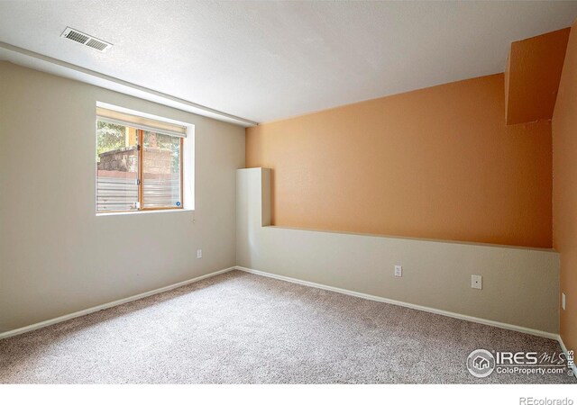 carpeted empty room featuring a textured ceiling