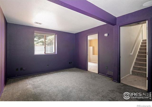 unfurnished bedroom featuring beamed ceiling, carpet floors, and a textured ceiling