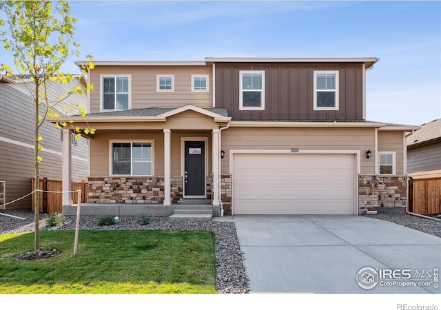 view of front of home featuring a porch, fence, concrete driveway, stone siding, and board and batten siding