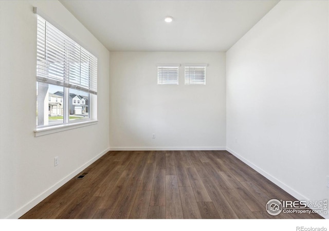 unfurnished room with wood finished floors, visible vents, and baseboards