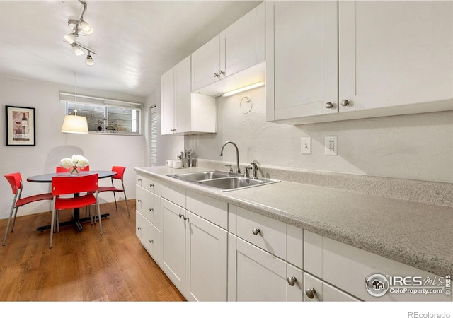 kitchen featuring white cabinetry, light wood-type flooring, sink, and track lighting