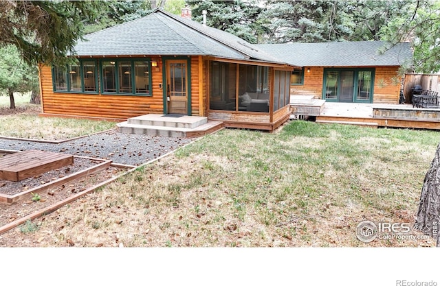 rear view of house with a wooden deck, a sunroom, and a lawn