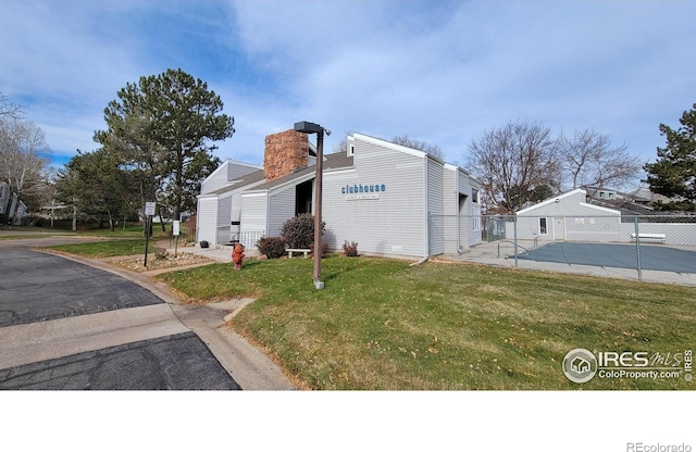 view of side of property with a chimney, a yard, and fence