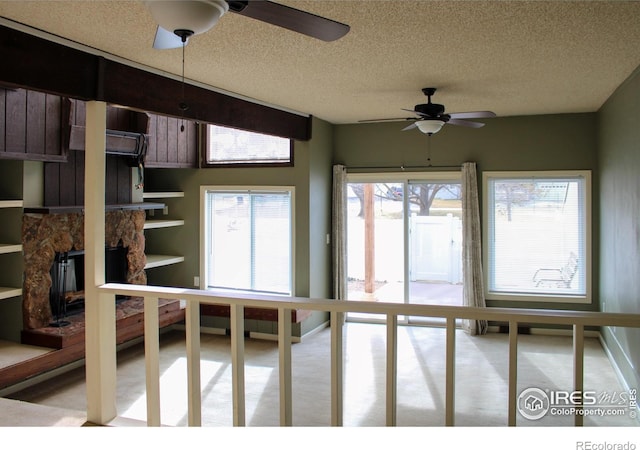 interior space with ceiling fan and a stone fireplace