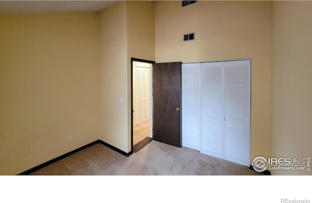 unfurnished bedroom featuring baseboards, a closet, light carpet, and visible vents