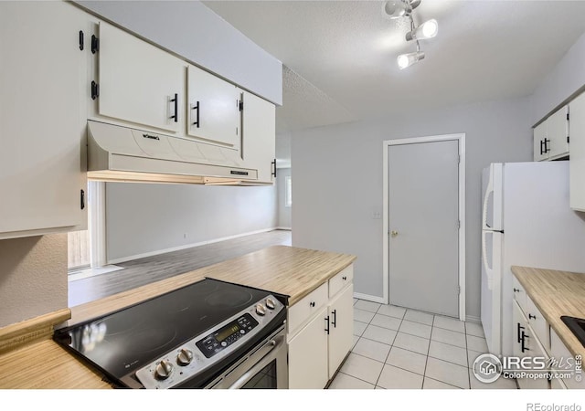 kitchen with a textured ceiling, light tile patterned floors, white refrigerator, white cabinets, and stainless steel electric range