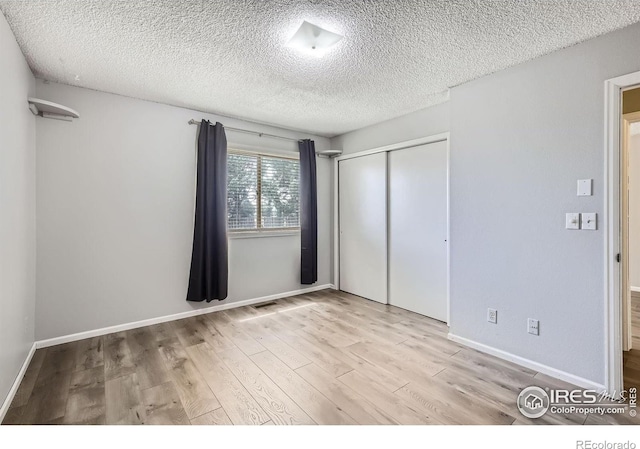 unfurnished bedroom featuring a textured ceiling, light hardwood / wood-style floors, and a closet