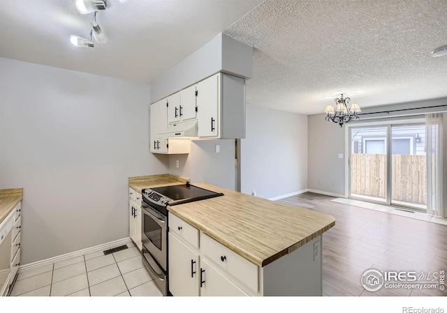 kitchen featuring light countertops, electric range, open floor plan, white cabinets, and under cabinet range hood