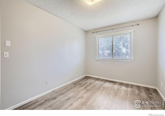 unfurnished room featuring light hardwood / wood-style floors and a textured ceiling