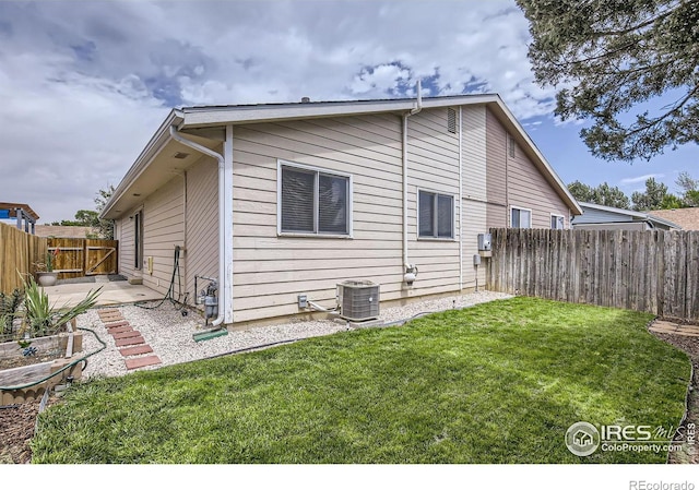 rear view of property with central AC unit, a patio area, and a yard