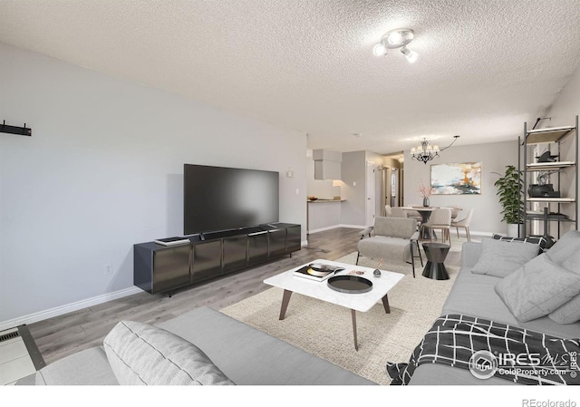 living room featuring a notable chandelier, baseboards, and wood finished floors