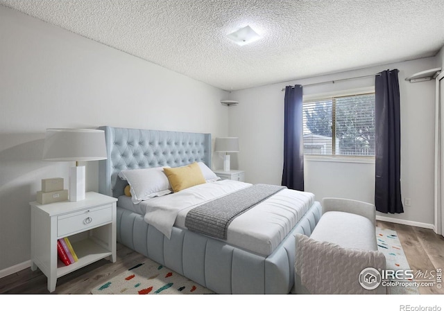 bedroom with hardwood / wood-style floors and a textured ceiling