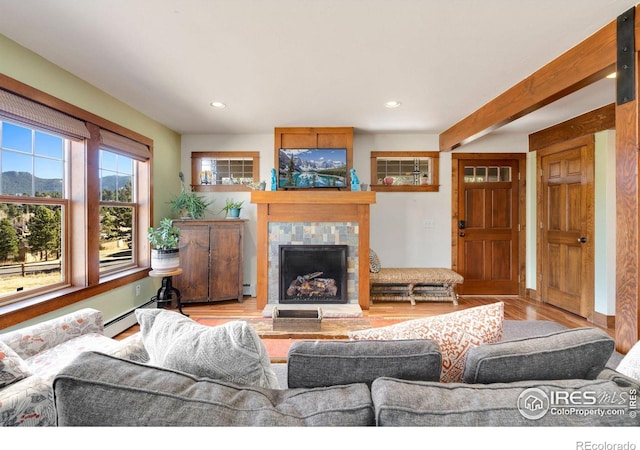 living room featuring light wood-type flooring, recessed lighting, a baseboard radiator, and a tile fireplace